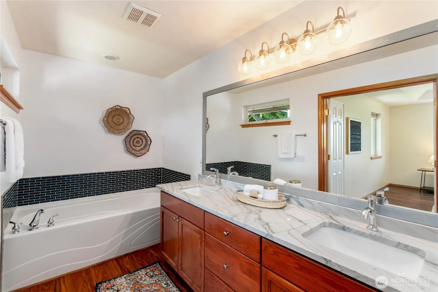 Remodeled primary bath with quartz double vanity and a tiled soaking tub.